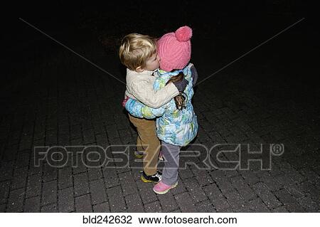 Stock Image - Boy ad girl hugging outdoors at night. Fotosearch