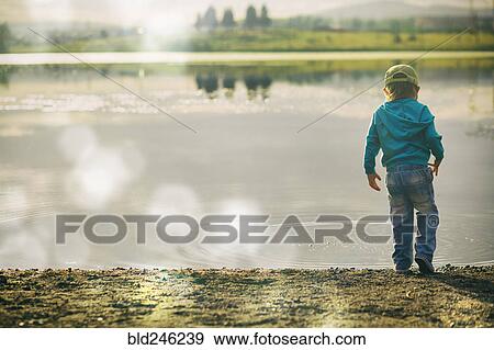 Boy watching ripples in lake View Large Photo Image Stock Photo - Boy watching ripples in lake. Fotosearch