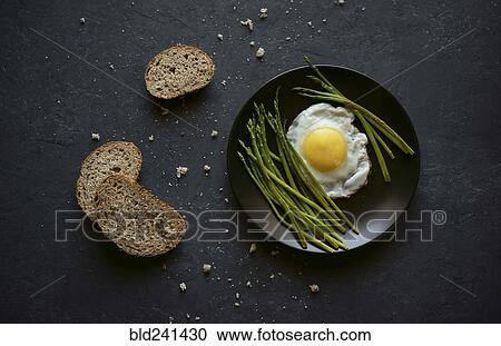 Bread and crumbs near plate with fried egg and asparagus View Large Photo Image Stock Image - Bread and crumbs near plate with fried egg and asparagus. Fotosearch