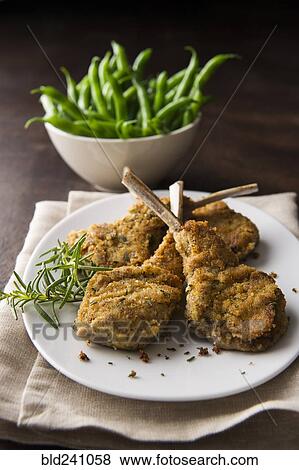 Stock Photo - Breaded lamb chops on plate with bowl of green beans. Fotosearch