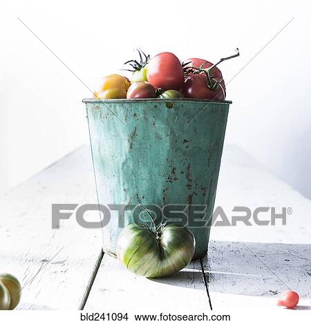 Picture - Bucket of fresh tomatoes on wooden table. Fotosearch
