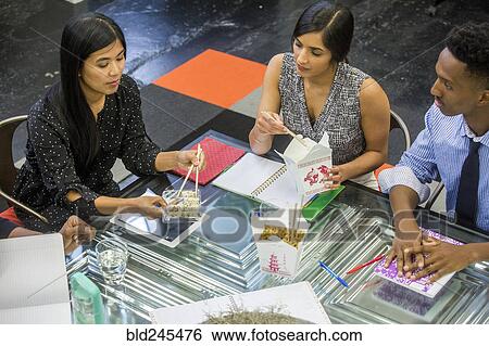 Stock Photograph - Business people eating food during meeting. Fotosearch