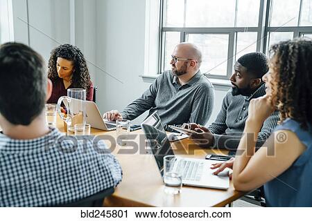 Stock Image - Business people listening in meeting. Fotosearch