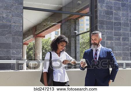 Stock Image - Business people standing near office building. Fotosearch