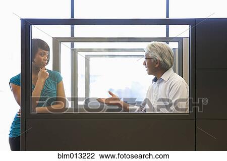 Stock Image - Business people talking in office cubicle. Fotosearch