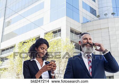Business people using cell phones near office building View Large Photo Image Picture - Business people using cell phones near office building. Fotosearch