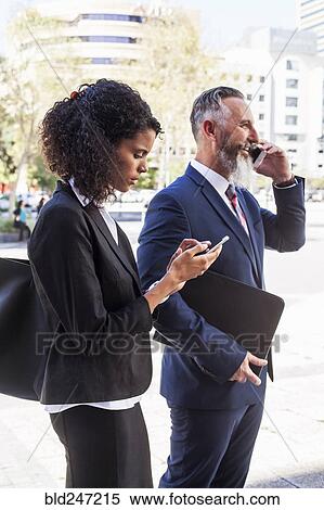 Stock Photography - Business people using cell phones outdoors. Fotosearch