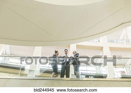 Stock Photography - Business people using digital tablet in lobby. Fotosearch