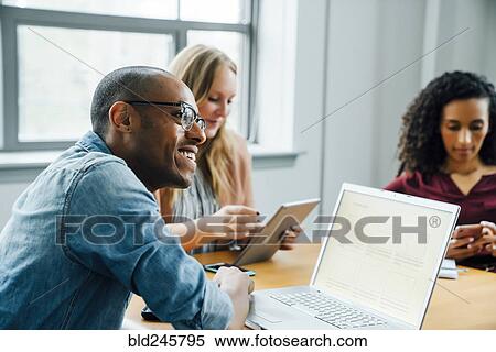 Stock Photography - Business people using technology in meeting. Fotosearch
