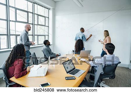 Stock Photo - Business people using whiteboard in meeting. Fotosearch