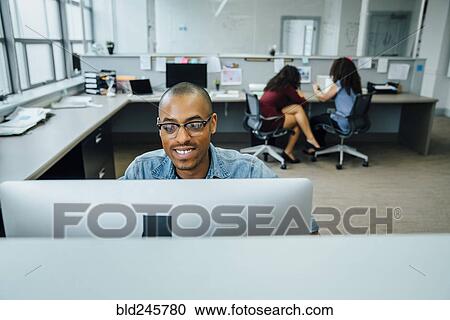 Stock Image - Businessman using computer in office. Fotosearch