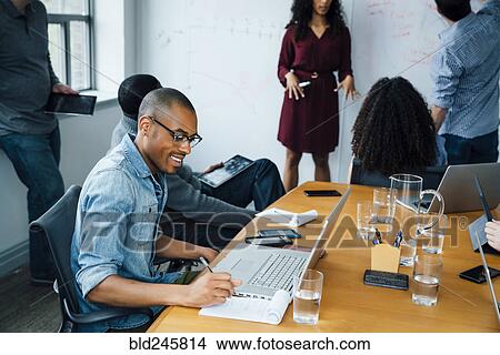 Picture - Businessman writing notes in meeting. Fotosearch