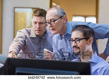 Stock Image - Businessmen talking in office near computer. Fotosearch