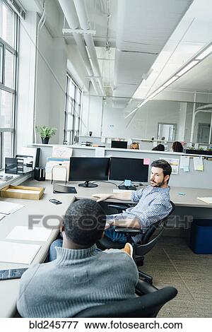 Stock Photo - Businessmen talking in office. Fotosearch