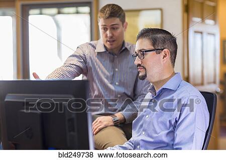 Stock Photo - Businessmen talking near computer in office. Fotosearch