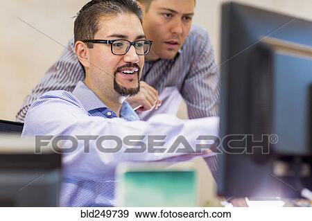 Stock Photo - Businessmen talking near computer in office. Fotosearch