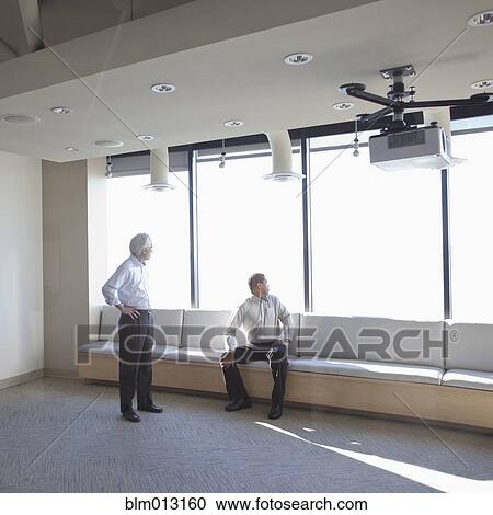 Stock Image - Businessmen together in office lobby. Fotosearch