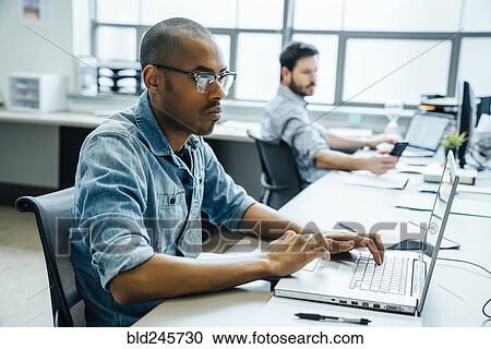 Stock Image - Businessmen using technology in office. Fotosearch