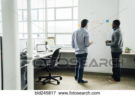 Stock Photo - Businessmen using whiteboard in office. Fotosearch