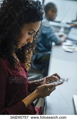 Businesswoman using cell phone in office View Large Photo Image Stock Photo - Businesswoman using cell phone in office. Fotosearch