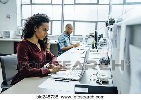 Stock Photo - Businesswoman using laptop in office. Fotosearch