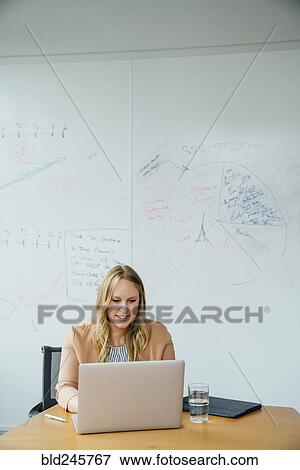 Stock Photo - Businesswoman using laptop in conference room. Fotosearch