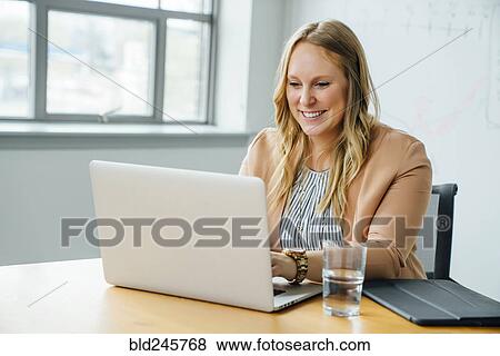 Stock Photo - Businesswoman using laptop in conference room. Fotosearch