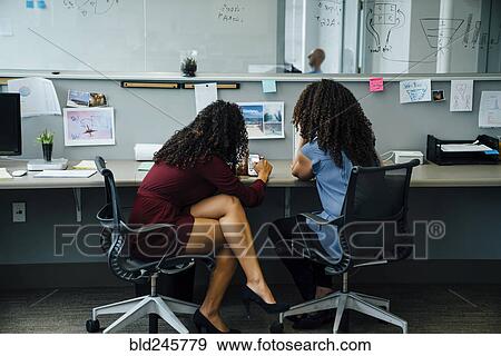 Stock Photo - Businesswomen using cell phone in office. Fotosearch