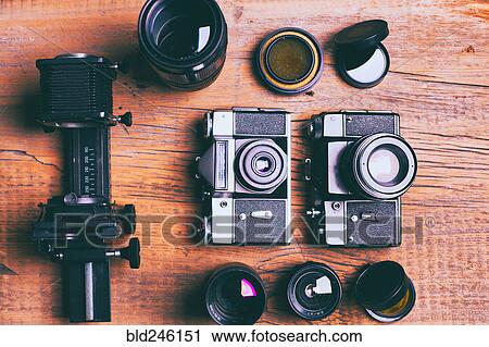 Stock Image - Cameras and lenses on wooden table. Fotosearch