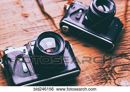 Stock Photograph - Cameras and straps on wooden table. Fotosearch
