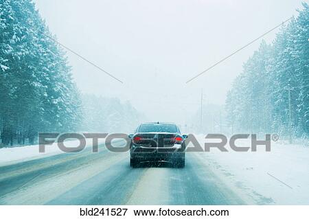 Stock Photo - Car driving on tree-lined road in winter. Fotosearch