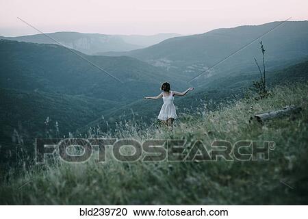 Stock Image - Carefree Caucasian woman walking on mountain. Fotosearch