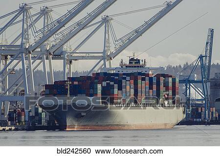 Stock Image - Cargo containers on freighter at shipping port. Fotosearch