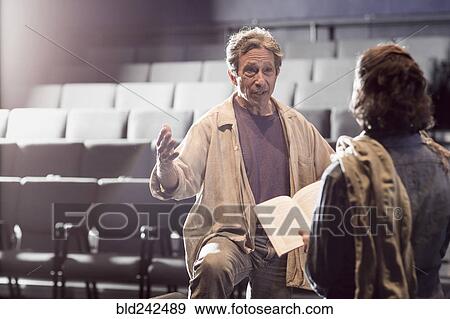 Stock Photo - Caucasian actors rehearsing with script in theater. Fotosearch