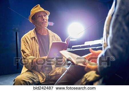 Stock Photo - Caucasian actors rehearsing with scripts in theater. Fotosearch