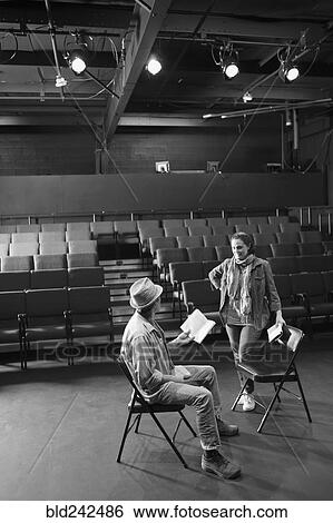 Stock Photograph - Caucasian actors rehearsing with scripts in theater. Fotosearch