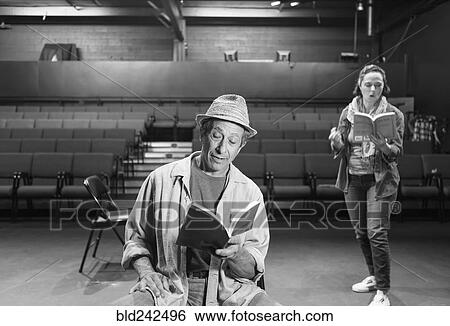 Stock Photograph - Caucasian actors rehearsing with scripts in theater. Fotosearch