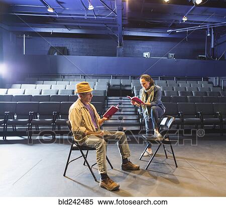 Stock Photography - Caucasian actors rehearsing with scripts in theater. Fotosearch