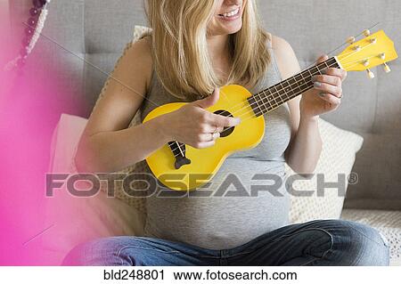 Caucasian and expectant mother playing small yellow guitar View Large Photo Image Stock Image - Caucasian and expectant mother playing small yellow guitar. Fotosearch