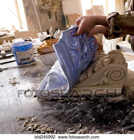 Stock Image - Caucasian artist lifting mold from plaster. Fotosearch