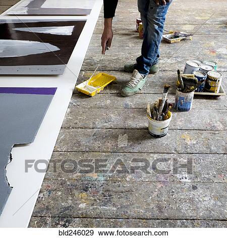 Stock Photo - Caucasian artist painting with paint roller. Fotosearch