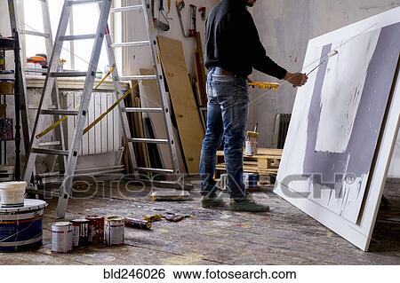 Stock Photograph - Caucasian artist painting with paint roller. Fotosearch