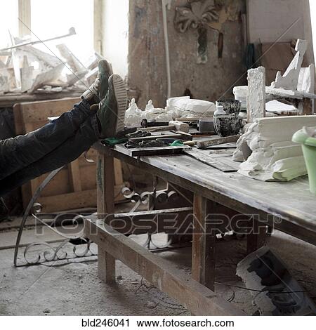 Stock Image - Caucasian artist relaxing with feet on table. Fotosearch