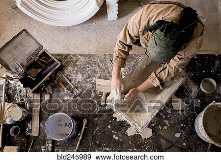 Stock Photo - Caucasian artist spreading plaster into mold with hands. Fotosearch