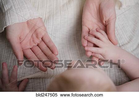 Stock Photography - Caucasian baby boy holding hand of mother. Fotosearch