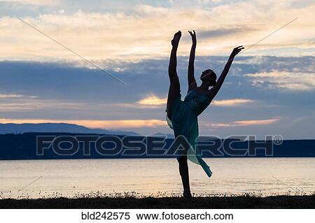 Stock Photography - Caucasian ballerina dancing on beach at sunset. Fotosearch