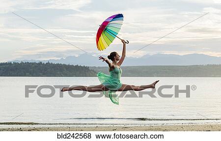 Caucasian ballerina jumping with multicolor umbrella on beach View Large Photo Image Stock Photo - Caucasian ballerina jumping with multicolor umbrella on beach. Fotosearch