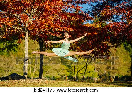Caucasian ballerina leaping under branches in park View Large Photo Image Stock Photography - Caucasian ballerina leaping under branches in park. Fotosearch