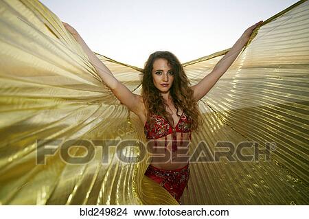 Picture - Caucasian belly dancer holding cape on beach. Fotosearch