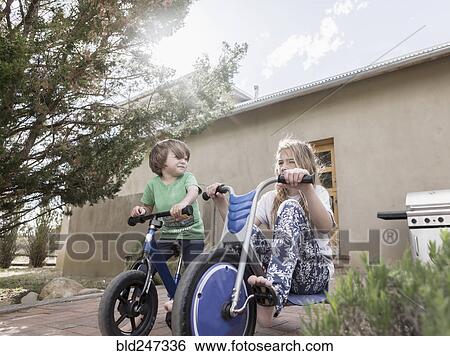 Stock Photograph - Caucasian boy and girl riding bicycles near house. Fotosearch